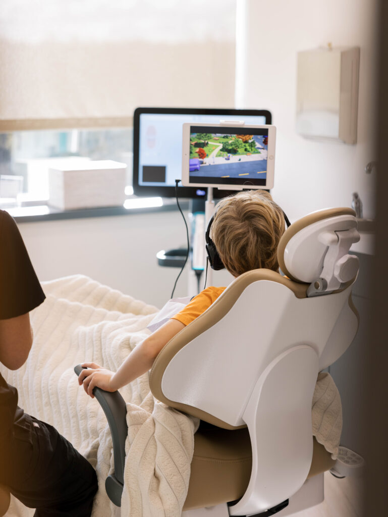 child in dental chair watching screen