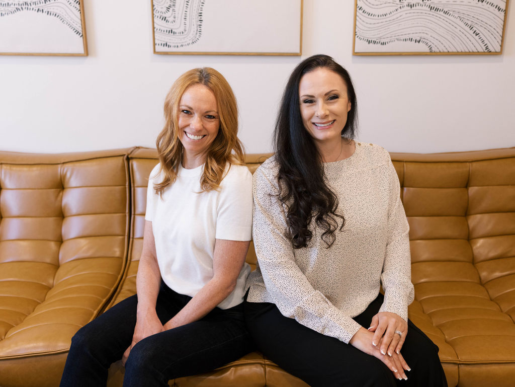 two women sitting on a couch smiling